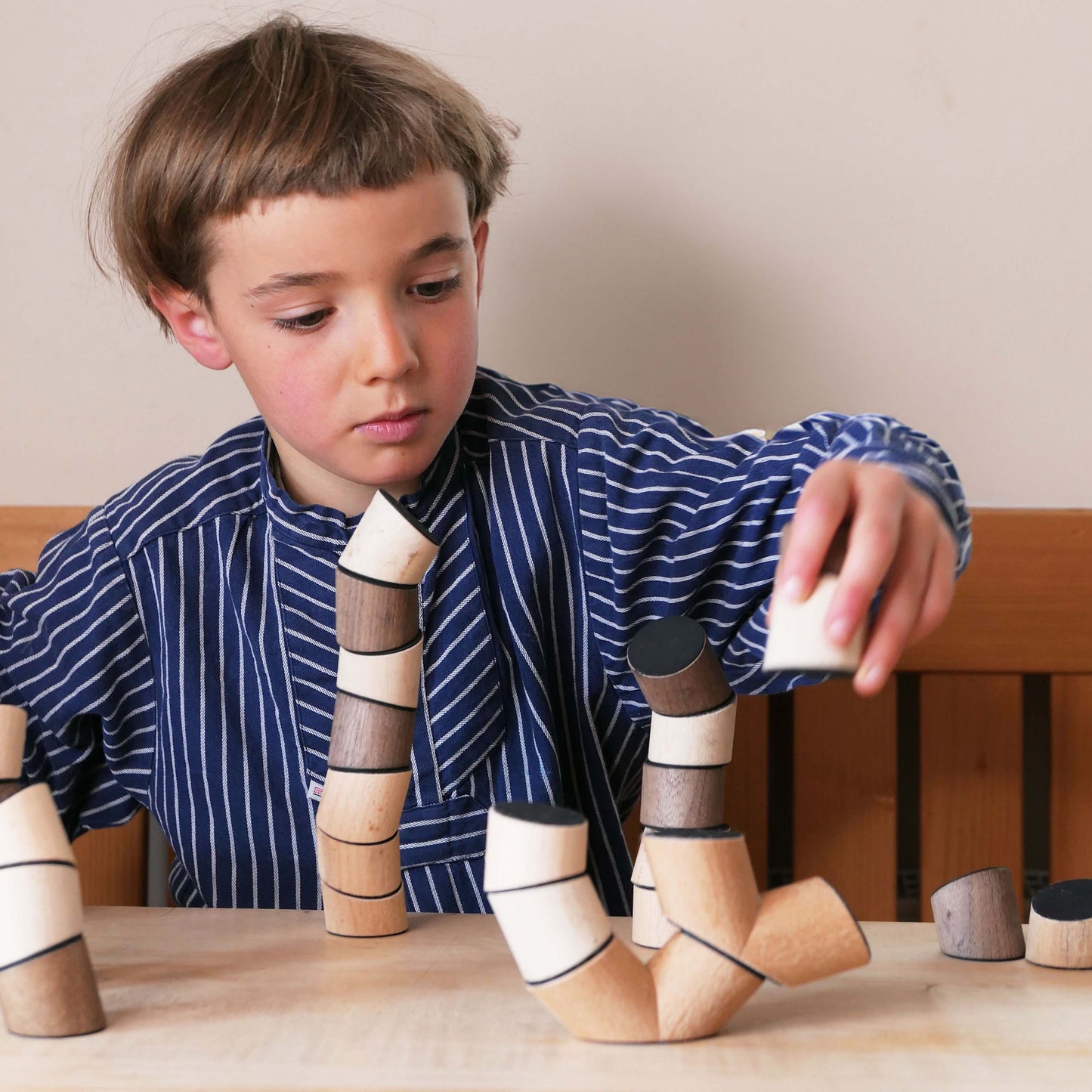 Ein Kind spielt mit dem Loggos Stapelspiel aus Buchen- und Nussholz