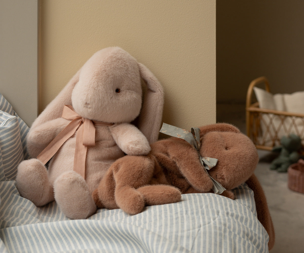Maileg brauner schlafender Plüschhase kuschelt mit einem weiteren Maileg Plüschhasen auf einem Bett im Kinderzimmer