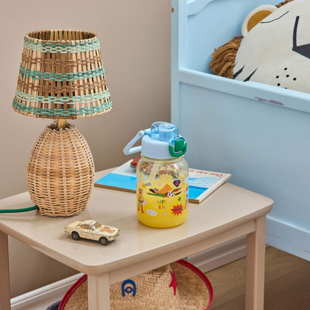 Trinkflasche von Rice in Blau mit „Hero“-Aufdruck, mit Orangensaft befüllt und dekorativ auf einem Nachttisch platziert