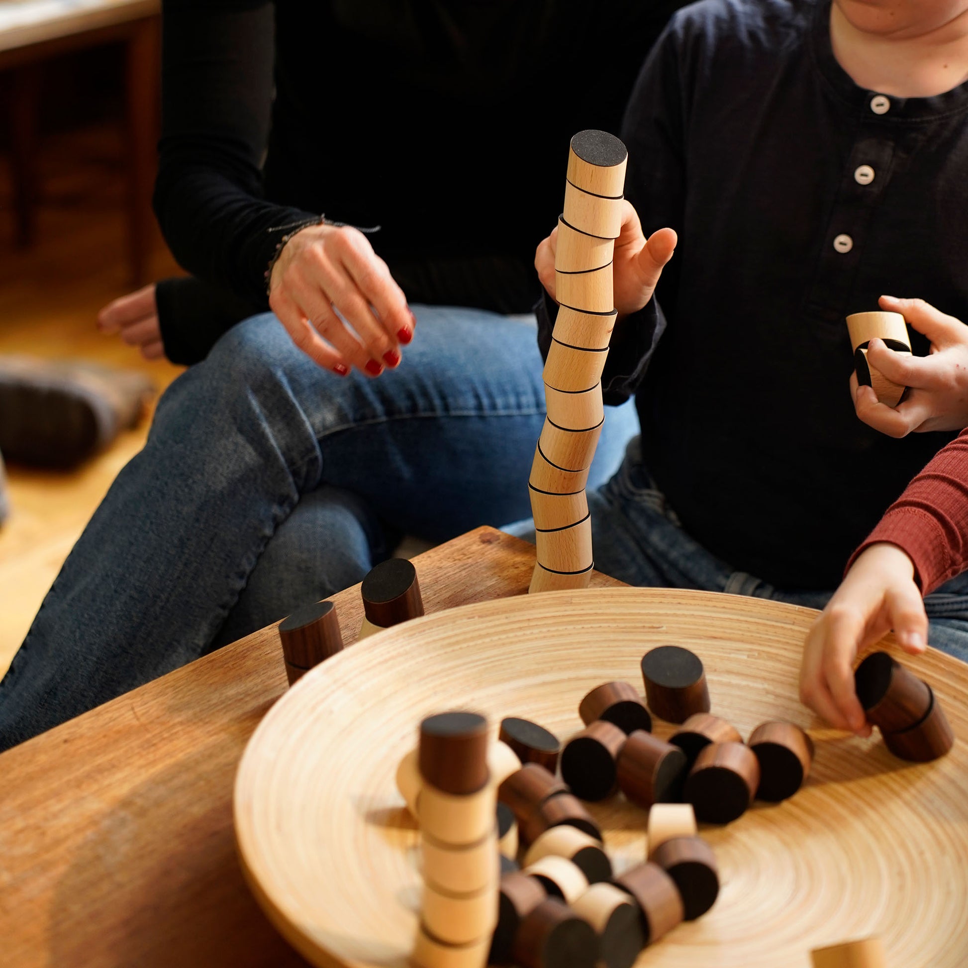 Ein Familie spielt gemeinsam mit dem Loggos Stapelspiel aus Buchen- und Nussholz