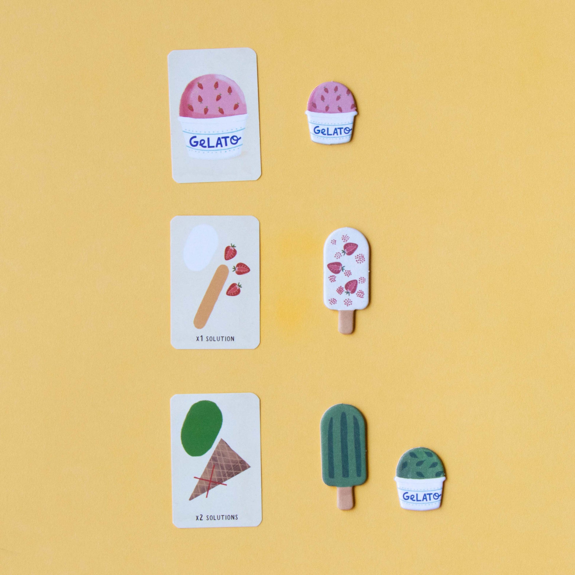 Drei Eiskarten aus dem Spiel „Gelato“ von Londji, die zusammen ein Eis mit verschiedenen Zutaten und Eiskugeln bilden