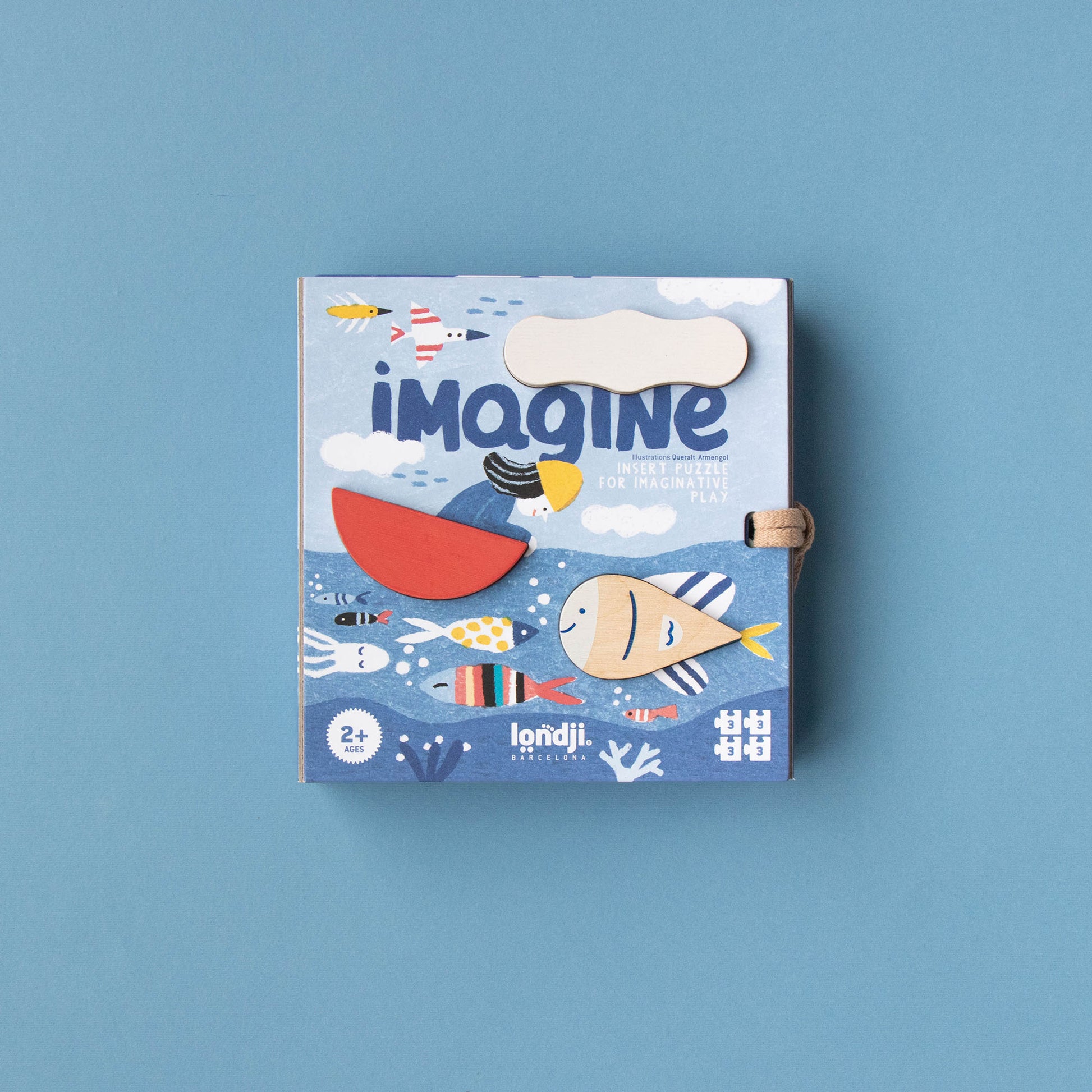 Spiel „Imagine“ von Londji, Vorderseite der Box zeigt drei Holzstücke, die je nach Fantasie eingesetzt werden können, in diesem Fall als Wolke, Boot und Fisch