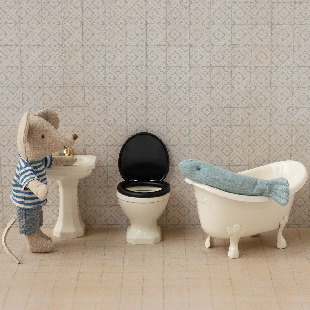 Kleiner Spielzeugfisch in einer weißen Miniatur-Badewanne, dekorativ arrangiert als verspieltes Accessoire.