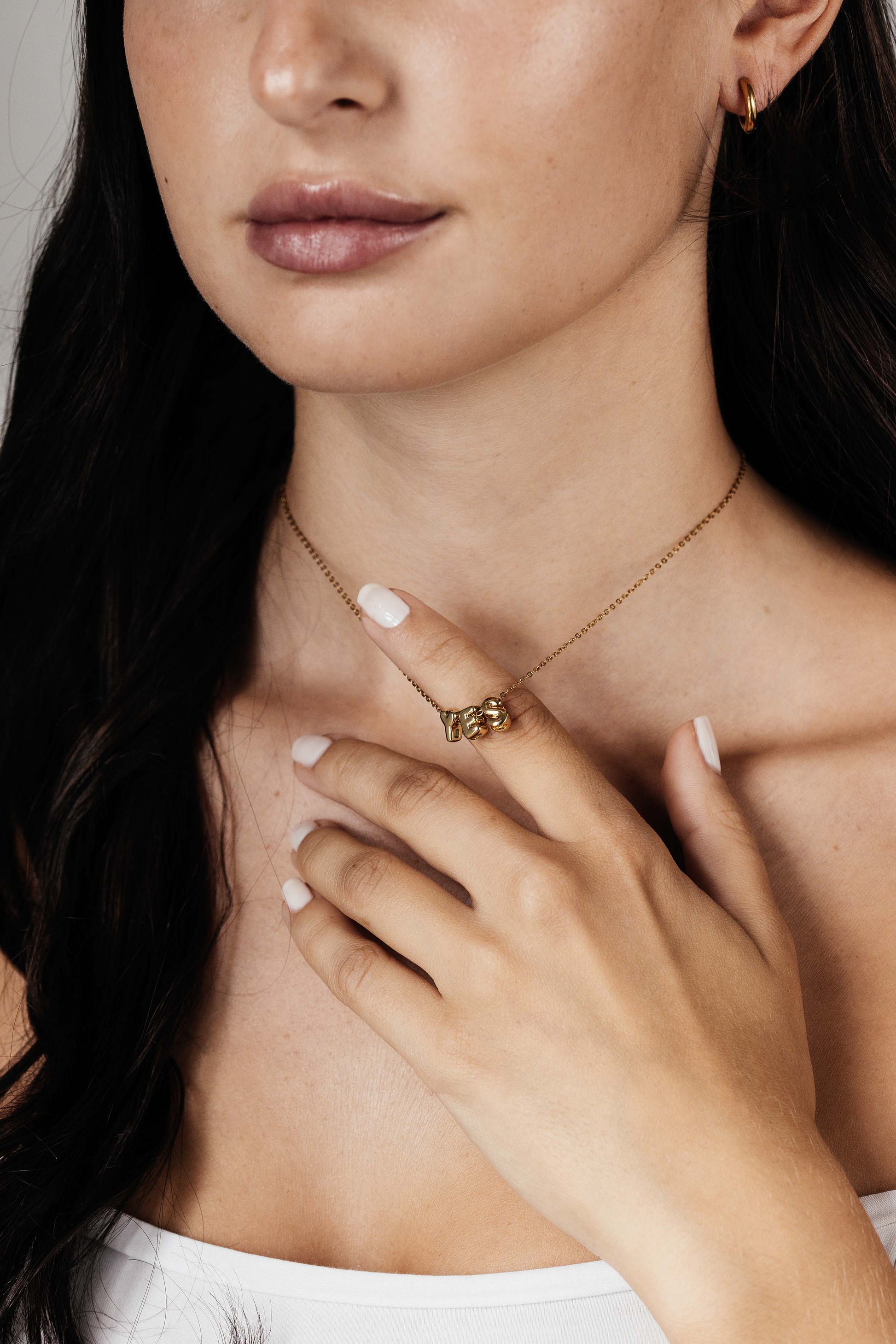 Goldene Halskette mit dem Wort ‚YES‘, getragen von einer Frau