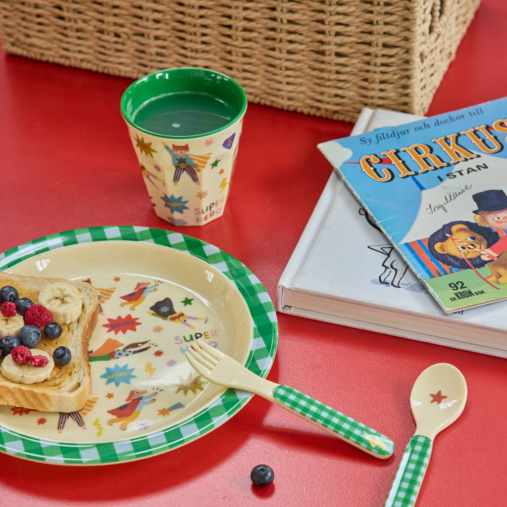 Melaminbecher von Rice in Grün mit Superhelden-Motiv, kombiniert mit passendem Teller und Besteck, liebevoll mit Essen arrangiert
