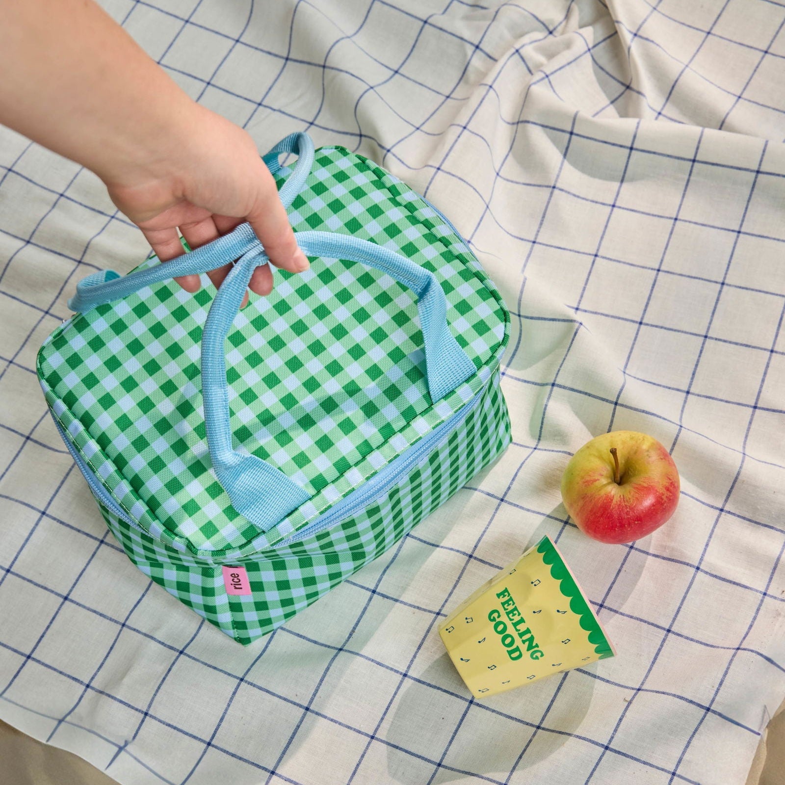 Moodbild mit einem liebevoll arrangierten Picknickkorb neben dem Melaminbecher von Rice, auf dessen Rückseite der Schriftzug „Feeling good“ zu sehen ist, in einer fröhlichen, sommerlichen Picknickszene