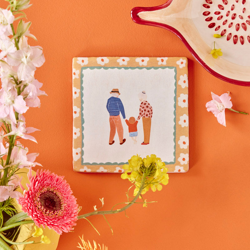 Storytiles Keramikfliese im Rahmen an einer orangefarbenen Wand aufgehängt, dekoratives Wandobjekt
